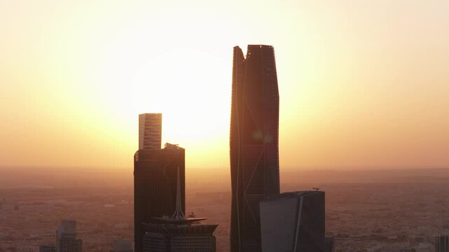 Aerial close view of KAFD towers with the sun moving between at sunset in Riyadh, Saudi Arabia