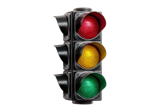 A classic three-light traffic signal, red, yellow, and green, set against a stark black background.  The lights are illuminated, and the casing shows signs of age or weathering