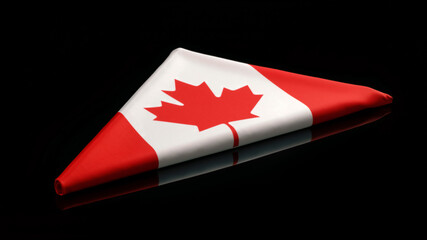 Folded Canadian flag on a reflective black background. Concept of honor, remembrance, and national pride.