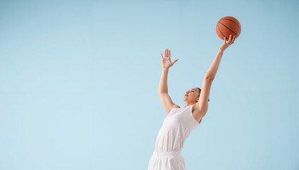 Young man jumping to shoot a basketball against a blue background