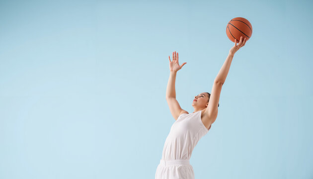 Young man jumping to shoot a basketball against a blue background  