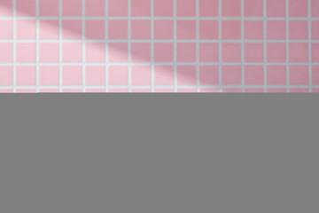 Minimal white podiums placed in front of a bold pink tile wall with strong diagonal light. A...