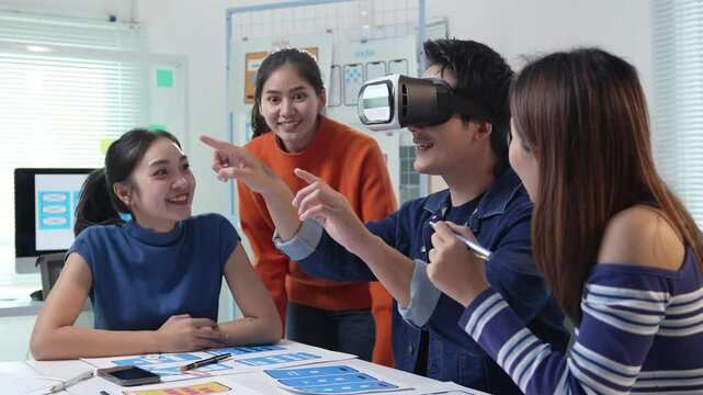 Professional asian design team evaluating virtual reality headset, collaborating on innovative metaverse technology within modern workplace environment