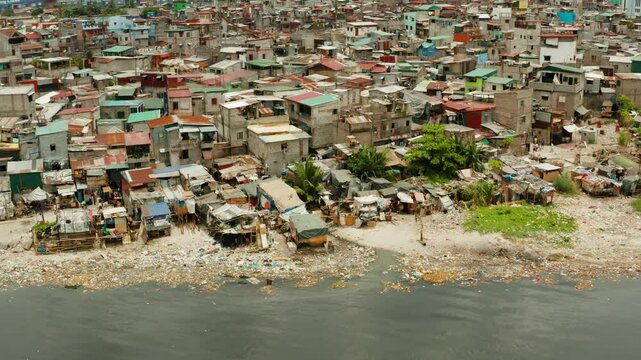 Slums with shacks of local residents and the river bank littered with garbage from above. Manila, Philippines.