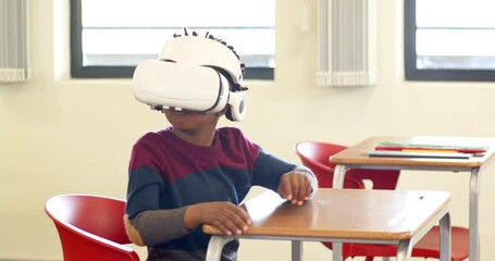 In school, african american boy using VR headset at desk, exploring virtual world - Powered by Adobe