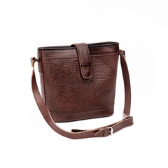 Beautiful dark brown leather shoulder bag with embossed decoration for women isolated on white...