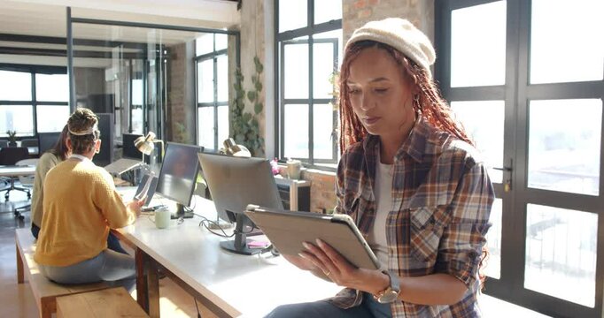 In modern office, diverse female team using tablets and computers collaborating on coding projects - Powered by Adobe