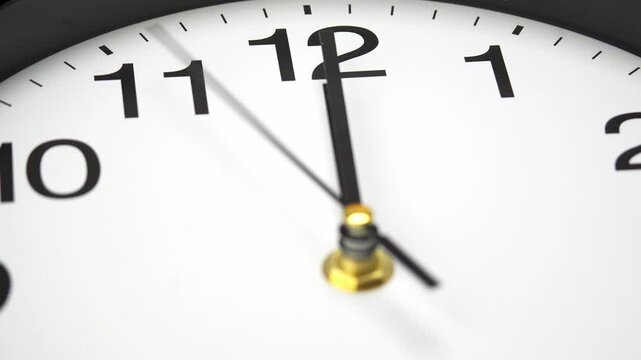 close-up view of an analog clock showing the time at exactly midnight with both hands aligned at twelve.