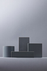 Vertical layout of stacked matte grey podiums in cylinder and cube shapes on soft neutral...