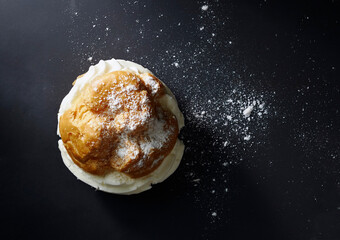 Cream-Filled Pastry with Powdered Sugar on Dark Surface