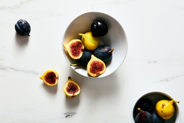 Fresh Black and Yellow Figs in Bowls on White Marble Surface
