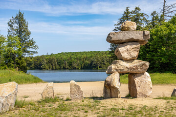 A serene lakeside view at Clear Lake in Muskoka, featuring a striking rock sculpture under a bright blue sky.