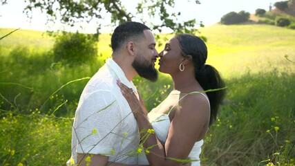 A loving and pregnant African American couple enjoys a delightful moment together outdoors, embracing their journey of love and anticipation for new beginnings on a warm and sunny day in nature