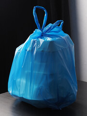 Blue plastic bag filled with lunch food in various containers resting on table.