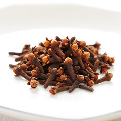 Fototapeta premium Dried cloves spice pile on white plate close up