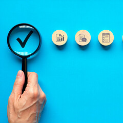 Hand holding magnifying glass focusing on checklist process steps