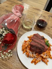 pasta and steak dinner with flowers and wine 
