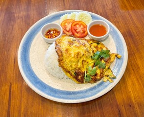 Thai crab omelette served with Thai jasmine rice, chili in fish sauce, spicy chili sauce, sliced cucumber and tomatoes. Thai food