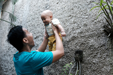 A Southeast asian father playing with baby boy in the home garden, doing everything together. Happy family 