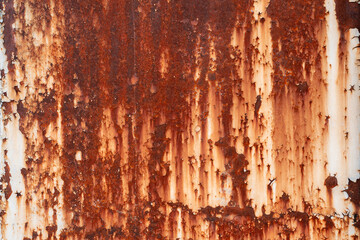 Aseverely rusted and peeling white metal surface with prominent vertical streaks of rust, creating...