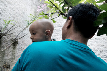 A Southeast asian father playing with baby boy in the home garden, doing everything together. Happy family 