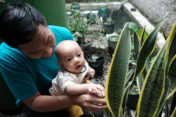 A Southeast asian father playing with baby boy in the home garden, doing everything together. Happy family 