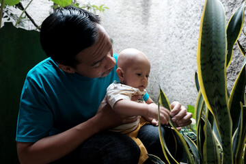 A Southeast asian father playing with baby boy in the home garden, doing everything together. Happy family 