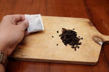 Closeup of hand man holding Tea bags and a bunch of loose tea in the wooden board. A quick and convenient way to brew tea.