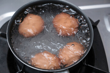 A pan with some boiling eggs on a stove. Chicken eggs in boiling water. Cooking process.