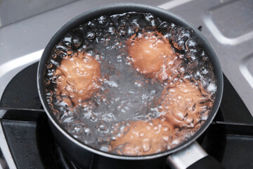 A pan with some boiling eggs on a stove. Chicken eggs in boiling water. Cooking process.