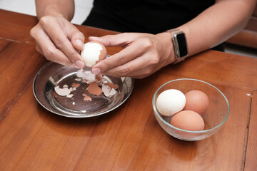 Close up of a man's hands peeling chicken boiled egg  on the kitchen table, prepares breakfast at...