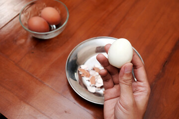 Close up of a man's hands holding chicken boiled egg  on the kitchen table, prepares breakfast at...