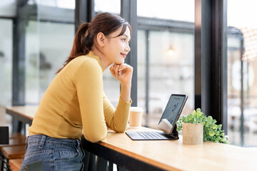 Fototapeta premium Young cheerful woman relaxing at cafe during online working with her laptop