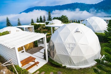 Phetchabun, Thailand - June, 06, 2025 :Scenic view of modern geodesic dome tents in an eco-resort nestled in lush green hills under a blue sky with scattered clouds at Phetchabun, Thailand