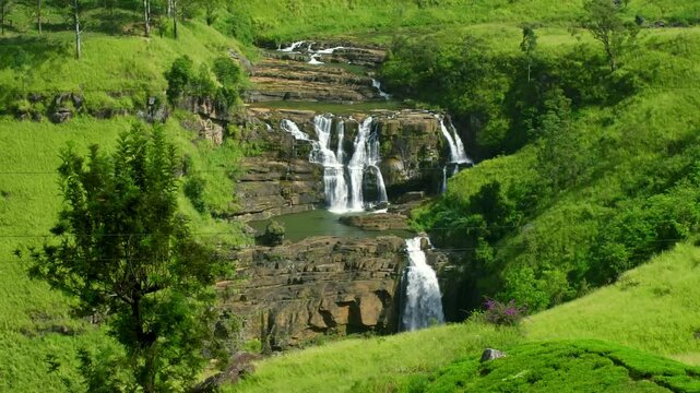 Multiple tiers of St. Clair's Falls cascading through a lush green valley in Sri Lanka, creating a stunning and serene landscape filled with vibrant tropical beauty