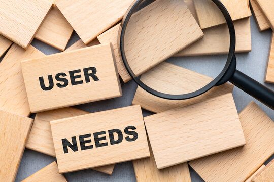 Wooden blocks with the words “User Needs” and a magnifying glass highlight the importance of user research and human-centered product or service design