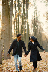 Loving black couple walking in park and enjoying autumn day