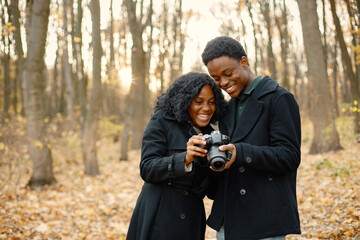 Black couple walking in park and looking in camera in their hands