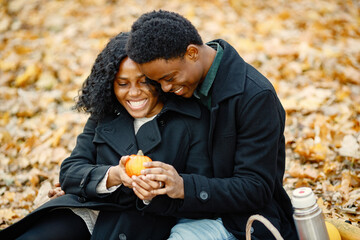 Loving black couple in autumn park looking on little pumpkin