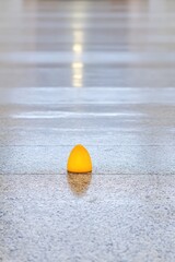 Yellow Egg-Shaped Object Illuminated by Spotlight on Reflective Floor