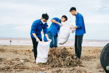 Volunteers clean up beach while collecting trash and debris during a community event on a cloudy day