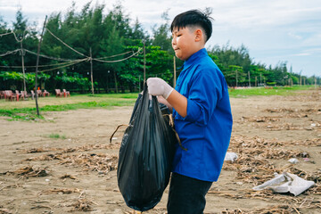 Young Asian boy participates in beach cleanup effort to promote environmental awareness and community responsibility