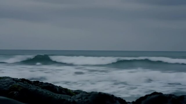 Serene ocean waves rolling onto a rocky shore under a moody sky