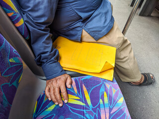 A bus passenger with a yellow folder, possibly job hunting in the city while facing employment...