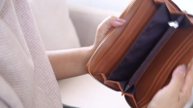 A woman opens her empty wallet, feeling worried about money, no job, spending too much, or being broke