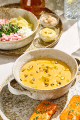 Okroshka ingredients and corn cream soup, bright natural lighting, overhead composition