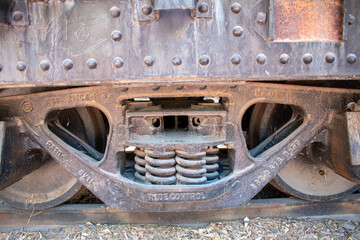 Fototapeta premium Detailed view of an old rusty train wheel suspension with visible springs and bolts in daylight
