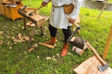 Traditional Woodworking Craftsman Using Axe and Adze. Man in Historical Costume Carving Wooden Log.