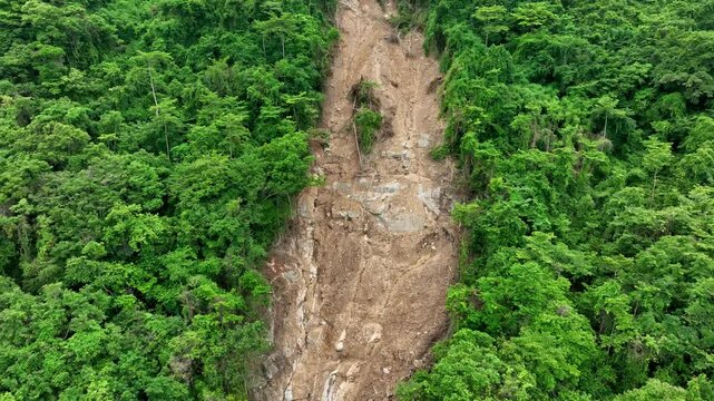 Aerial view of a forested hillside disrupted by a landslide due to heavy storms, demonstrating the powerful effects of extreme weather in destabilizing soil and vegetation. Thailand.
