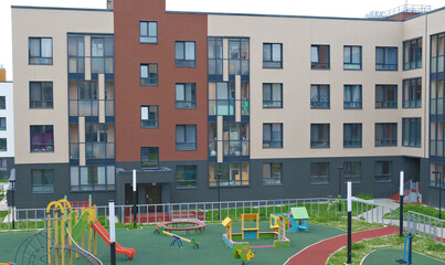Modern multi-storey residential building with a bright playground in the yard. emphasizing urban family life and interaction in the community.